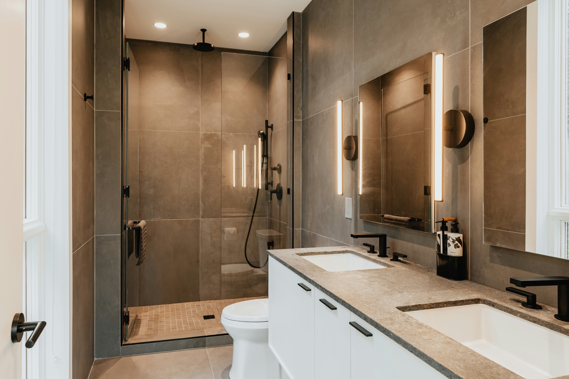 Modern bathroom remodel with dark tile and double vanity completed by EC Builders